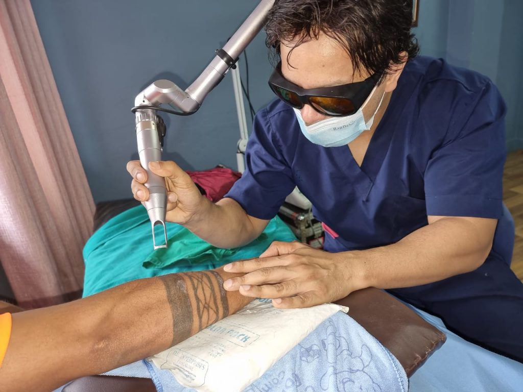 Dermatologist Dr. Rajan Tajhya performing laser tattoo removal procedure with a clinet. 