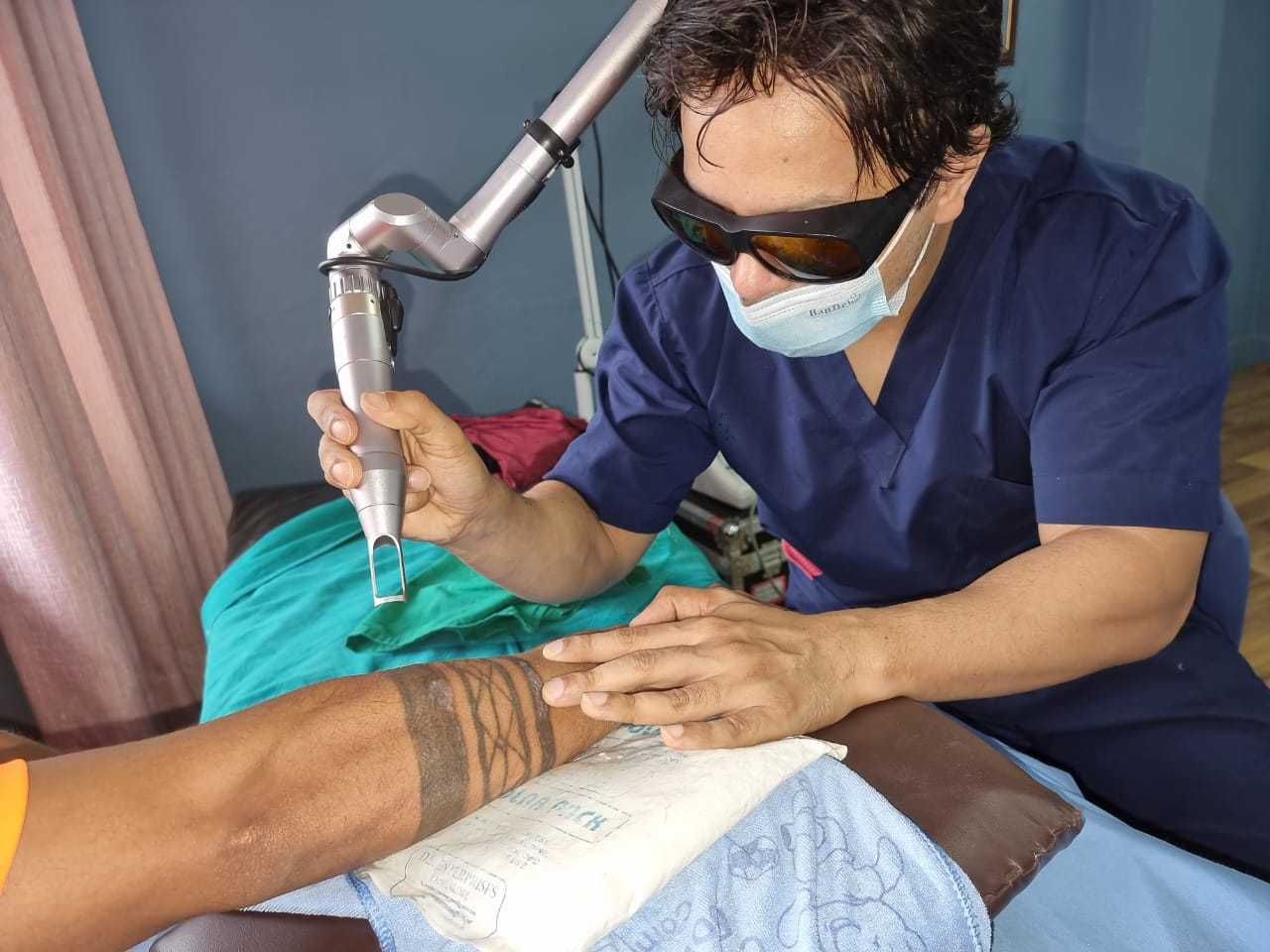 Dermatologist Dr. Rajan Tajhya performing laser tattoo removal procedure with a clinet.